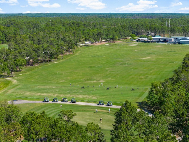 aerial view featuring a forest view and view of golf course
