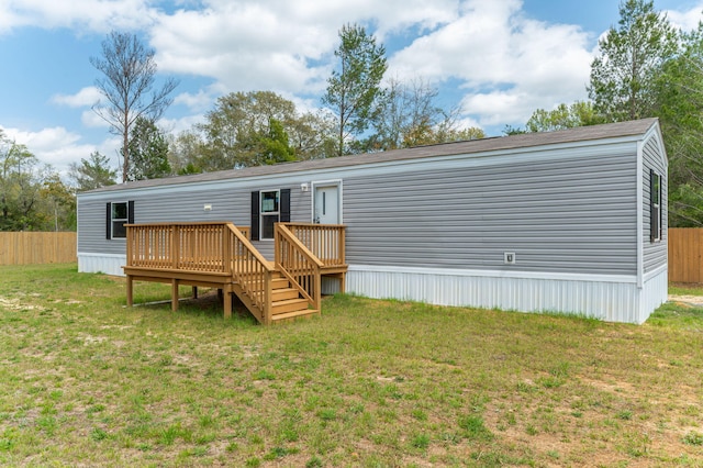 rear view of property with fence, a deck, and a yard