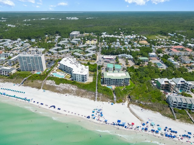 drone / aerial view with a wooded view, a view of the beach, and a water view