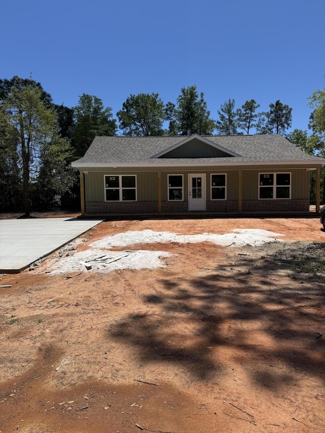 view of front of property with roof with shingles, brick siding, and board and batten siding