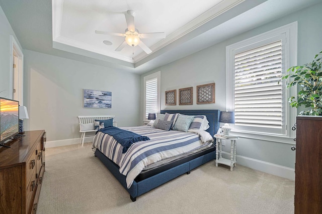 bedroom with baseboards, light carpet, multiple windows, and a raised ceiling