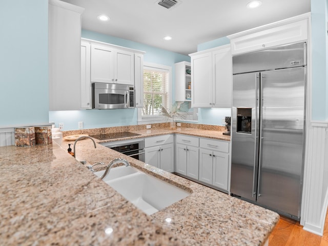 253 Salt Box Ln, Watersound, FL 32461 - kitchen with appliances with stainless steel finishes, light stone countertops, white cabinets, a sink, and recessed lighting