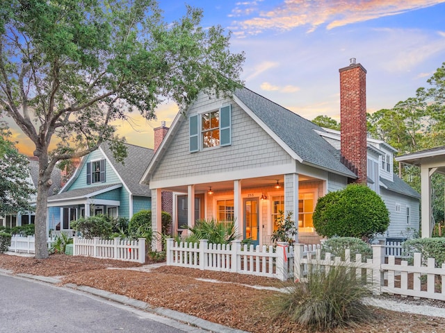 253 Salt Box Ln, Watersound, FL 32461 - view of front of property featuring a chimney, roof with shingles, a fenced front yard, and a porch