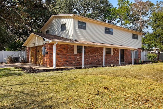 rear view of house featuring brick siding, a garage, fence, and a yard
