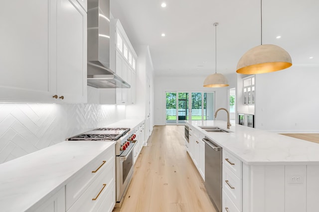 203 E Firethorn Cir Lot 24, Watersound, FL 32461 - kitchen featuring stainless steel appliances, wall chimney exhaust hood, backsplash, white cabinets, and light wood-type flooring