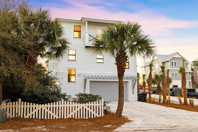 view of front of home with driveway, an attached garage, fence, and a balcony