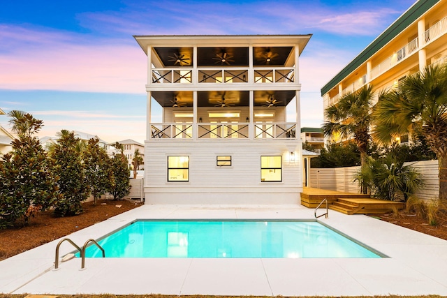back of house featuring a fenced backyard, a balcony, a fenced in pool, a ceiling fan, and a patio area