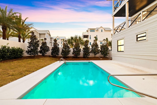 pool at dusk with a fenced backyard, a fenced in pool, a patio, and a lawn