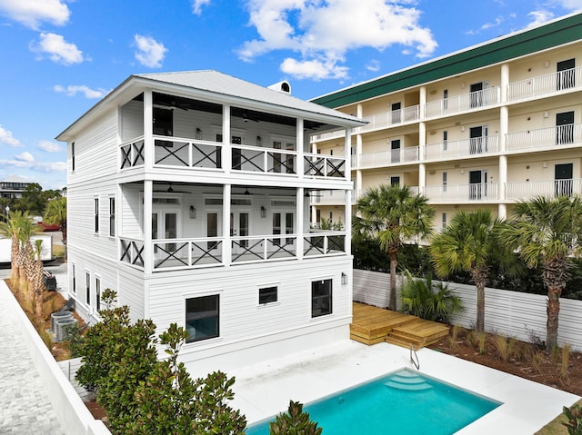 back of house featuring a balcony, fence, central air condition unit, ceiling fan, and a fenced in pool