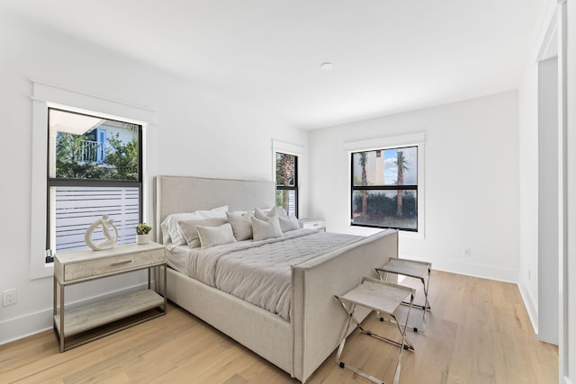 bedroom featuring baseboards, multiple windows, and light wood-type flooring