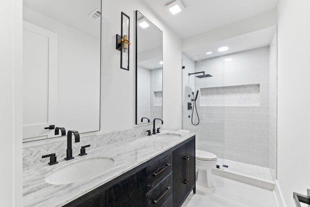 full bathroom featuring toilet, a sink, a tile shower, and visible vents