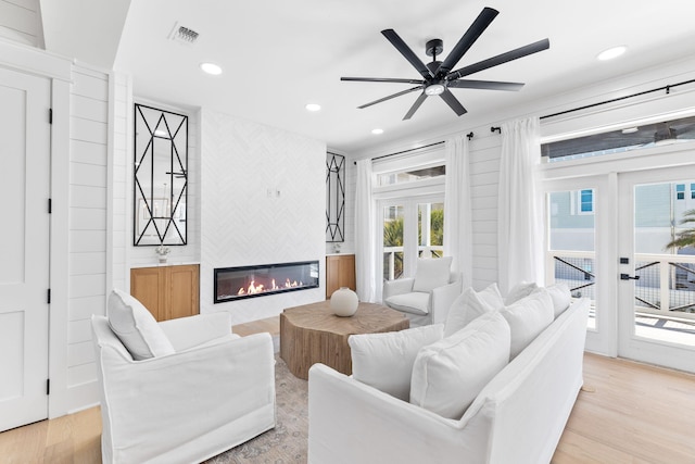 living area with a large fireplace, recessed lighting, light wood-style floors, and visible vents
