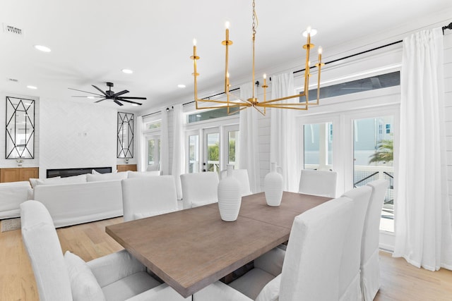 dining space with recessed lighting, ceiling fan with notable chandelier, light wood finished floors, and visible vents