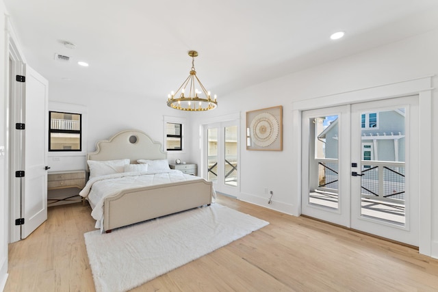 bedroom with multiple windows, a notable chandelier, access to outside, and light wood-type flooring