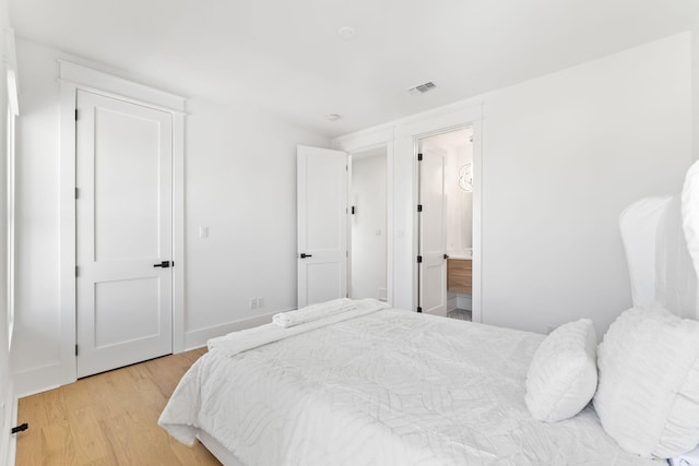 bedroom featuring baseboards, connected bathroom, visible vents, and light wood-style floors