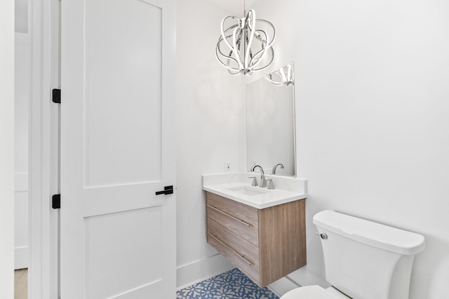 bathroom featuring toilet, an inviting chandelier, and vanity