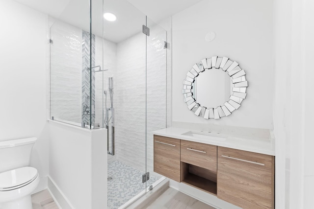 bathroom with baseboards, toilet, a stall shower, and vanity