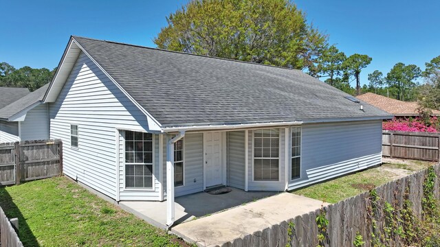 back of house with a patio, a shingled roof, a fenced backyard, and a yard