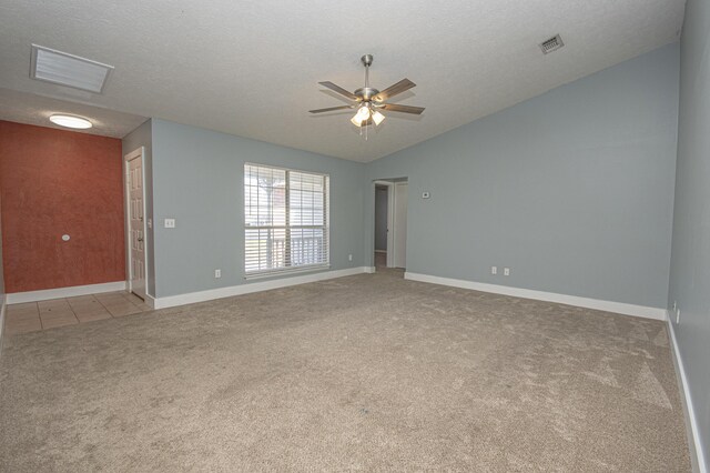empty room featuring light carpet, visible vents, lofted ceiling, and a ceiling fan