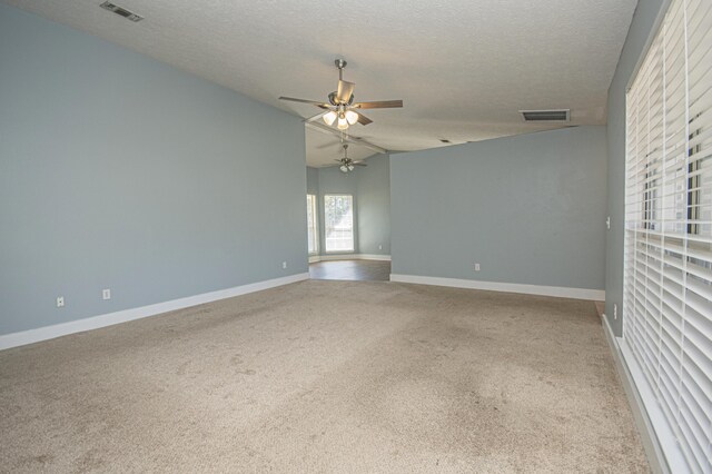 carpeted spare room featuring a textured ceiling, baseboards, ceiling fan, and visible vents