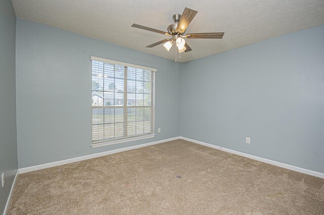 carpeted empty room featuring baseboards, ceiling fan, and a textured ceiling
