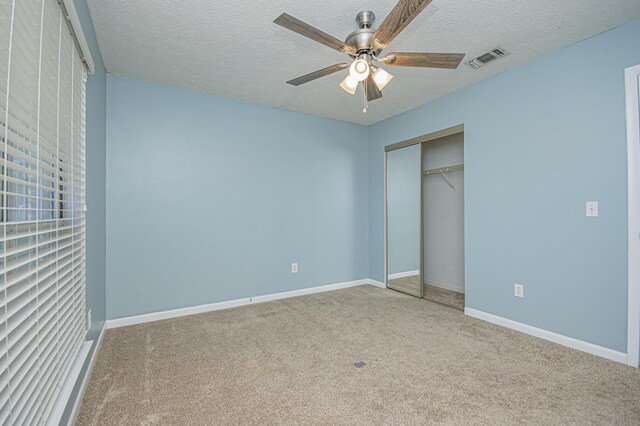 unfurnished bedroom with carpet flooring, baseboards, a closet, and a textured ceiling