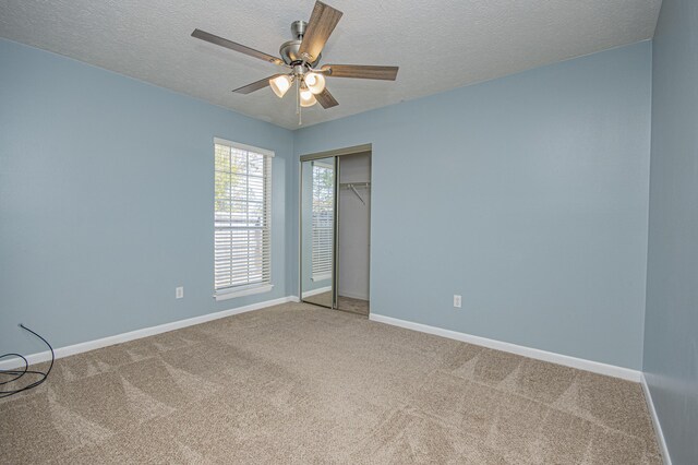unfurnished bedroom featuring carpet floors, a textured ceiling, baseboards, and a closet