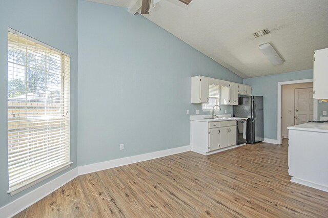 kitchen with light countertops, visible vents, light wood finished floors, a sink, and freestanding refrigerator