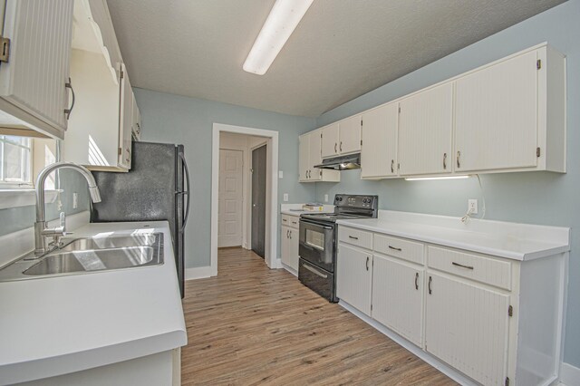 kitchen with light countertops, light wood finished floors, under cabinet range hood, a sink, and electric range