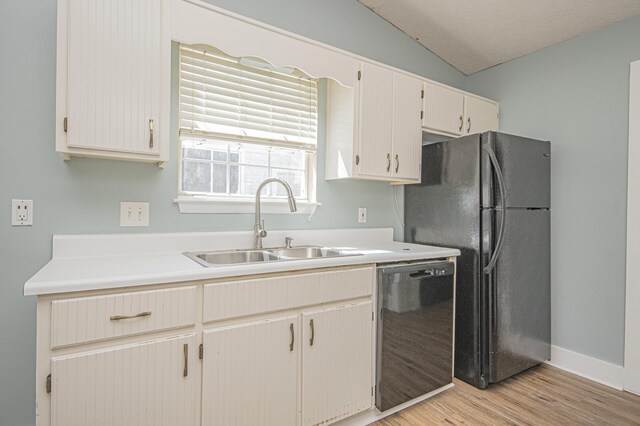 kitchen featuring light countertops, a sink, freestanding refrigerator, dishwasher, and light wood-type flooring