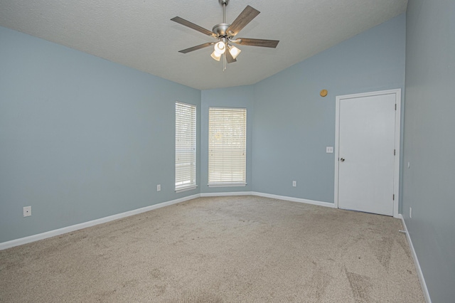 empty room with vaulted ceiling, carpet floors, a textured ceiling, baseboards, and ceiling fan