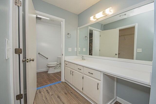 full bathroom with toilet, visible vents, wood finished floors, and vanity