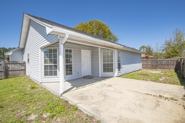 back of house with a fenced backyard, a yard, and a patio area