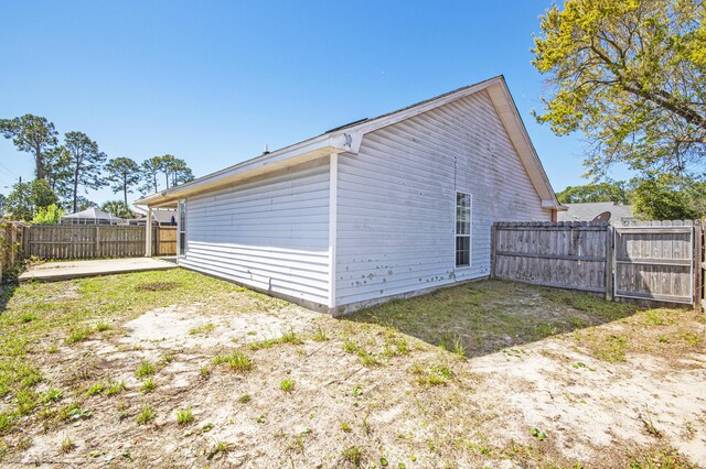 view of property exterior featuring a patio, a gate, and fence