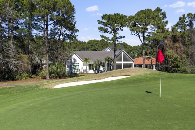view of property's community featuring a yard, view of golf course, and a garage