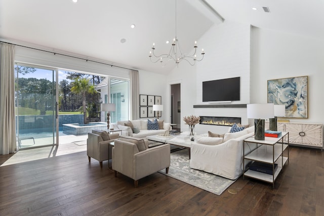 living area with a glass covered fireplace, an inviting chandelier, dark wood-style flooring, beam ceiling, and visible vents