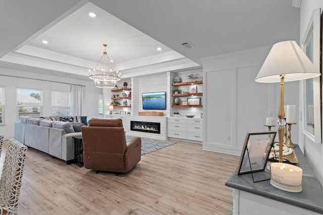 24 Palmer Ln, Santa Rosa Beach, FL 32459 - living room featuring a tray ceiling, a notable chandelier, crown molding, light wood finished floors, and a large fireplace