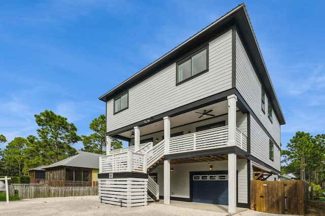 contemporary home featuring fence, stairs, an attached garage, and a ceiling fan