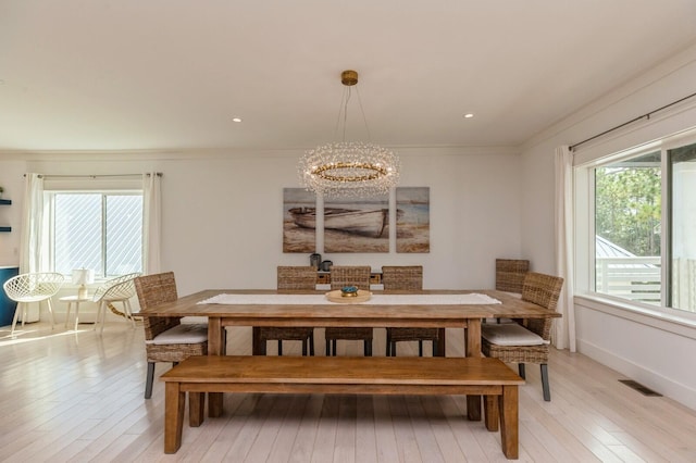 dining space featuring visible vents, baseboards, ornamental molding, light wood-type flooring, and an inviting chandelier