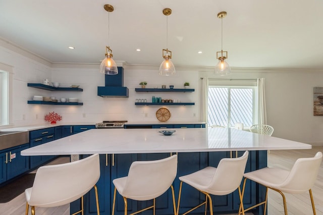 kitchen featuring blue cabinetry, open shelves, a spacious island, light wood-style flooring, and wall chimney exhaust hood