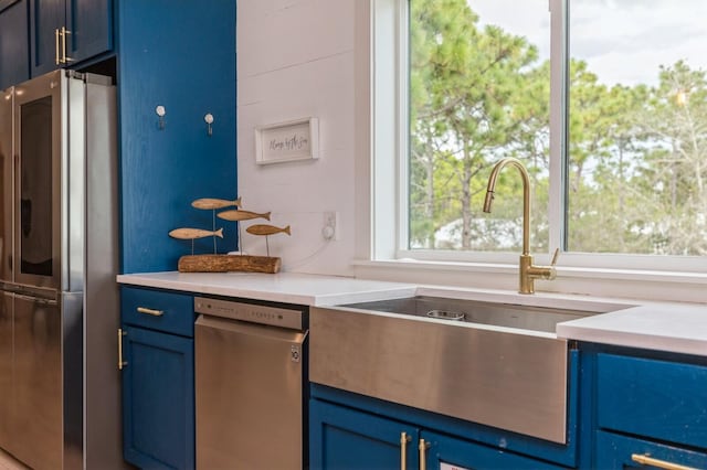 kitchen featuring light countertops, a sink, blue cabinets, and appliances with stainless steel finishes