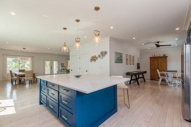 kitchen with ceiling fan, blue cabinets, light wood-type flooring, and freestanding refrigerator