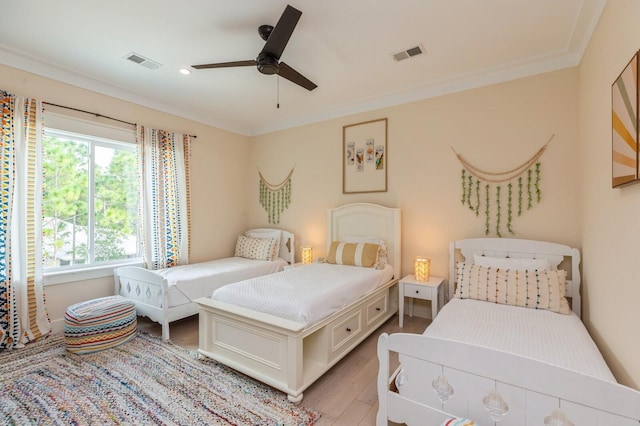 bedroom featuring light wood-style flooring, visible vents, and ornamental molding