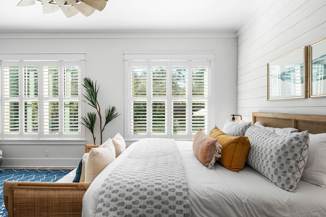 bedroom with crown molding, wood walls, ceiling fan, and baseboards