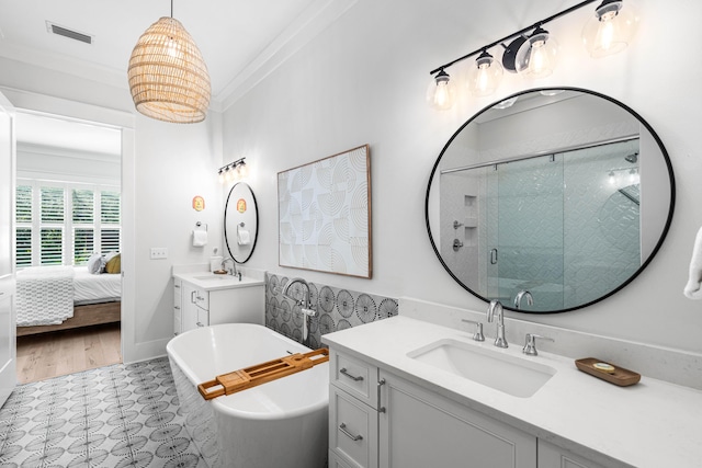 ensuite bathroom with visible vents, a freestanding tub, a sink, two vanities, and a stall shower