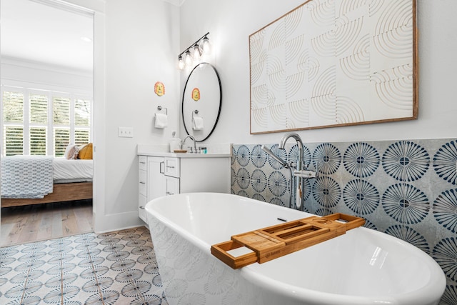 full bath featuring ensuite bath, vanity, baseboards, and a soaking tub