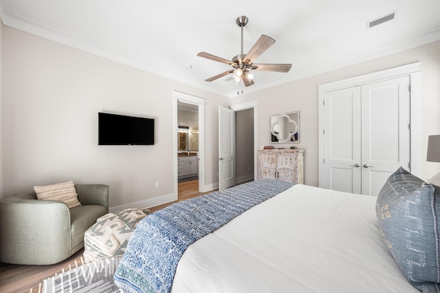 bedroom featuring crown molding, a closet, visible vents, wood finished floors, and baseboards