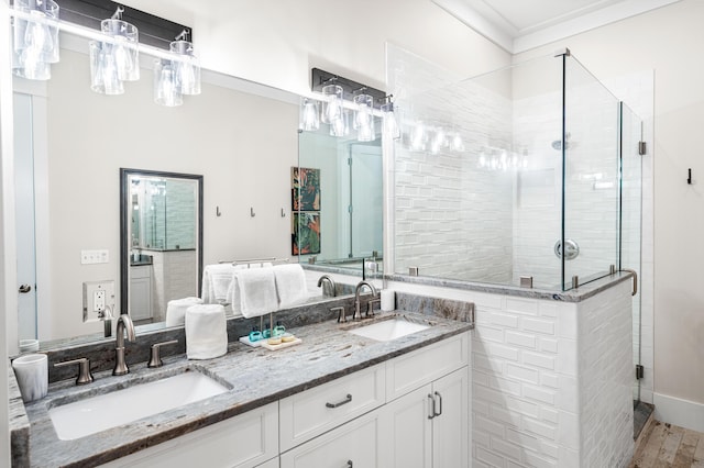 full bathroom with a stall shower, wood finished floors, double vanity, and a sink