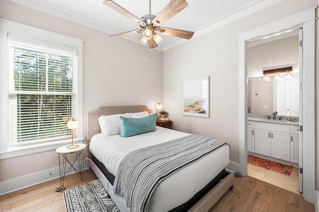 bedroom featuring light wood finished floors, ensuite bath, baseboards, and a sink