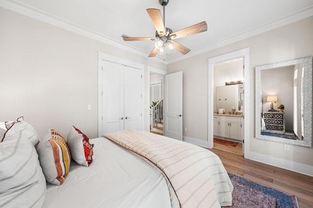 bedroom featuring connected bathroom, a closet, wood finished floors, a sink, and baseboards